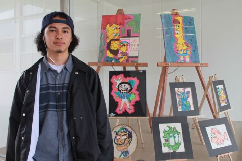 Humberto Juarez, a senior, stands near his art exhibit outside Room 92.