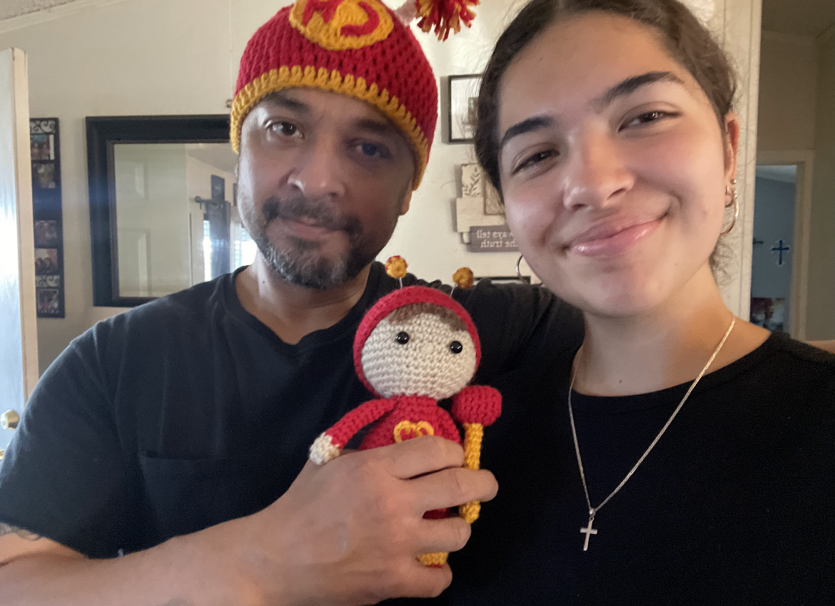 Guzman with her dad, holding crochet El Chapulin Colorado gifts 